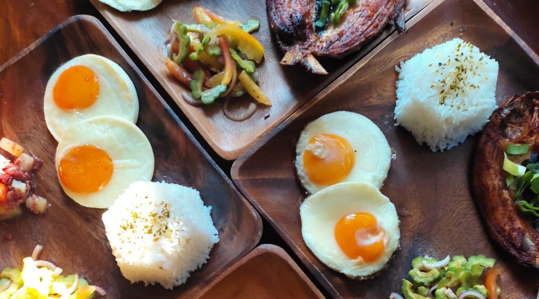 Breakfast laid out across the table — fried eggs, rice, bangus and ampalaya salad